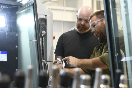 A faculty member and student completing hands-on work in a technical lab. 