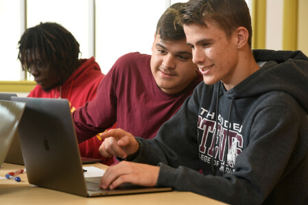 Two students work together on a project on a computer. 