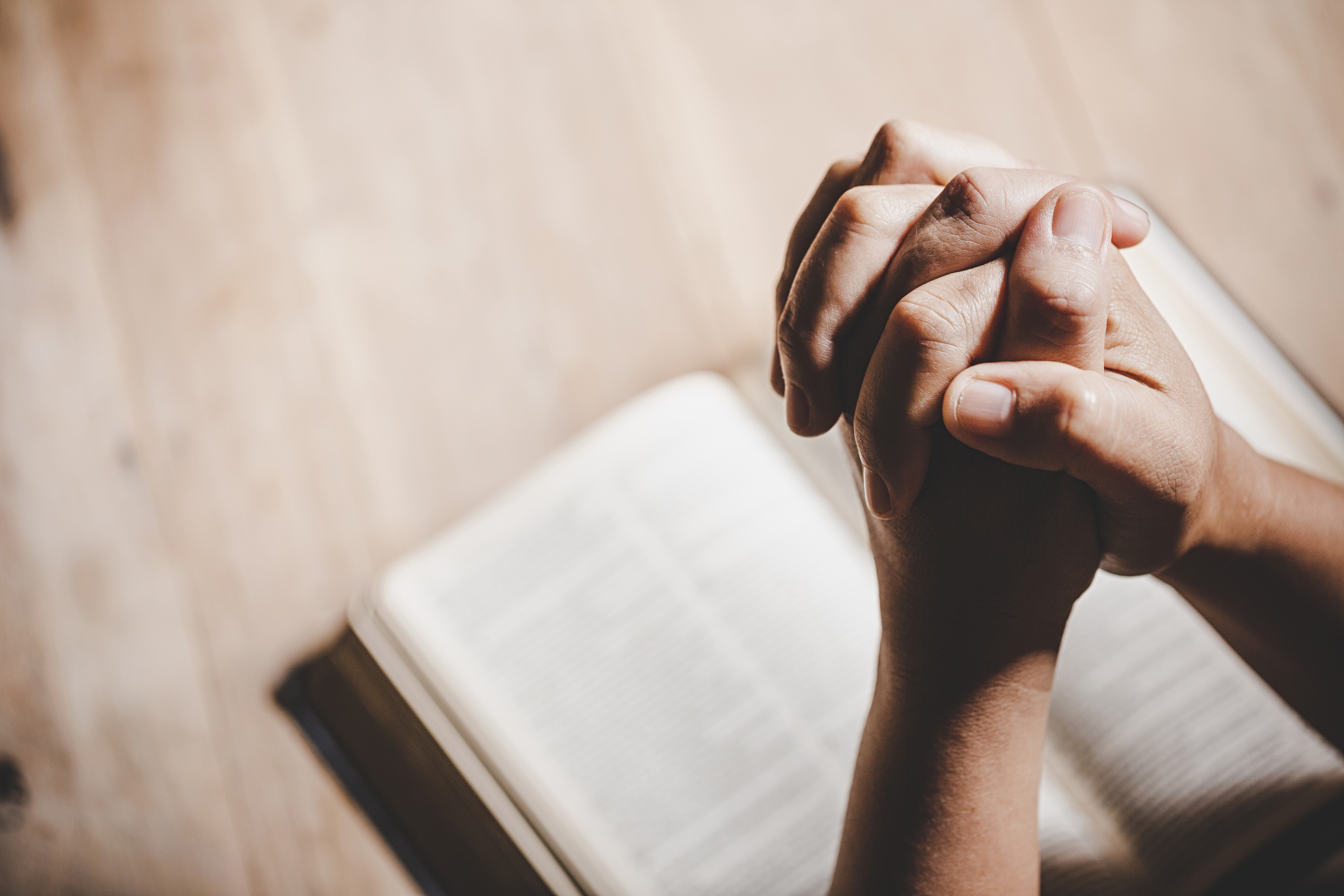 photo: praying hands over book