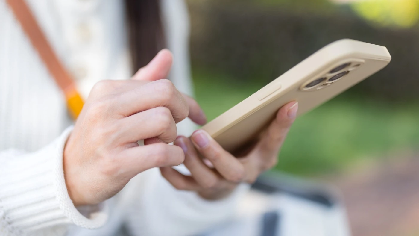 Person using a smartphone while reading and journaling