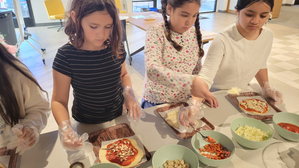 students cooking healthy pizzas for snack time in the kitchen of Dream School of the Arts San Diego