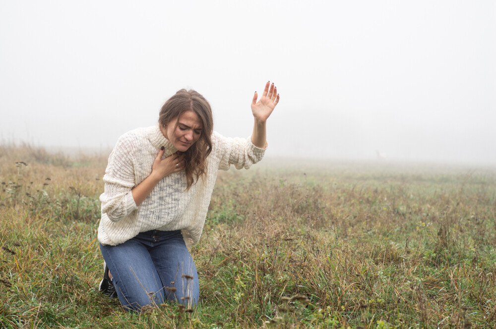 young-woman-in-field-on-knees-in-prayer