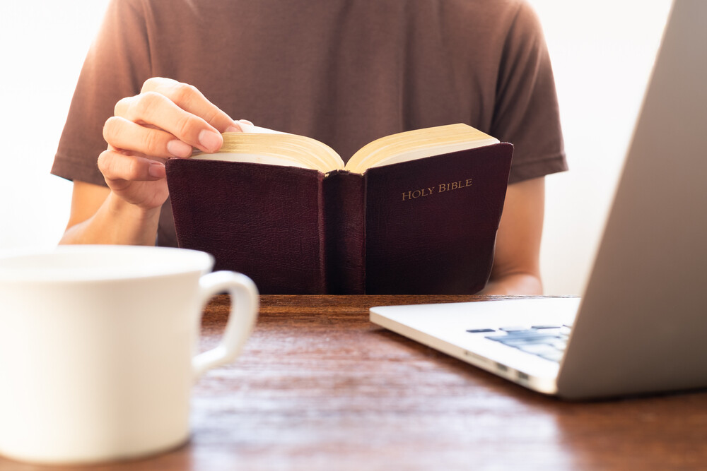 man-reading-Bible-with-laptop-and-coffee