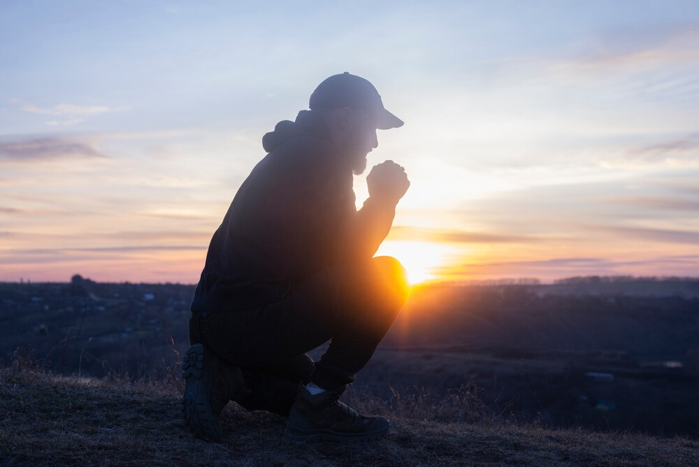 man-on-his-knees-praying-sunset-background