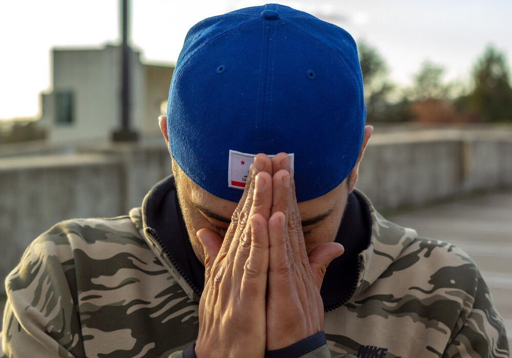 young-man-head-facing-down-and-hands-in-prayer