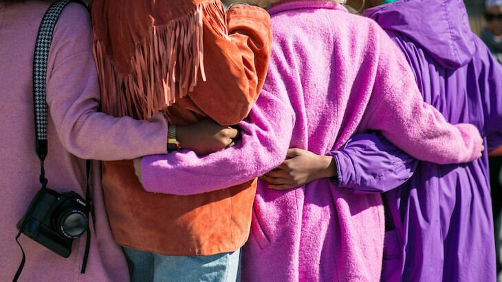 Women seen from behind, side-hugging