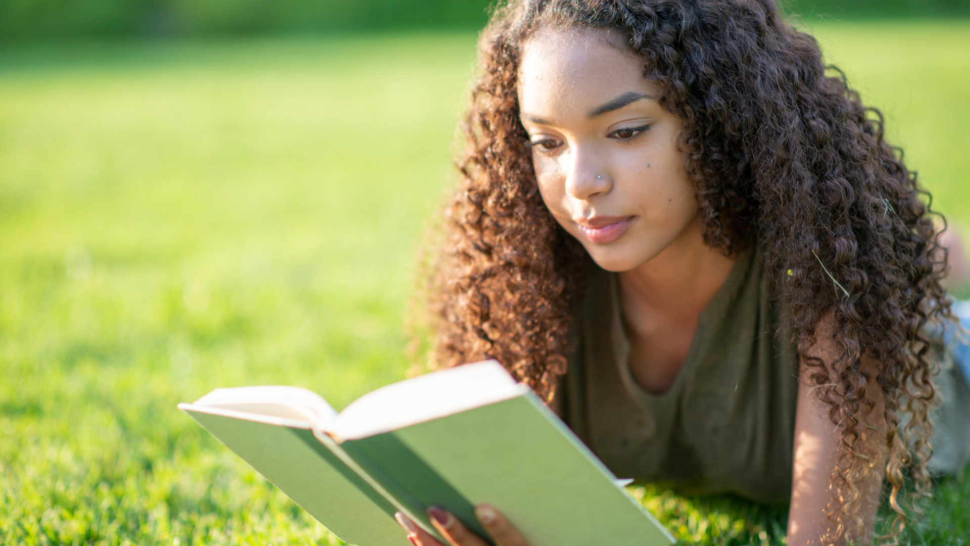 young-woman-reading-outside-in-the-grass-summertime