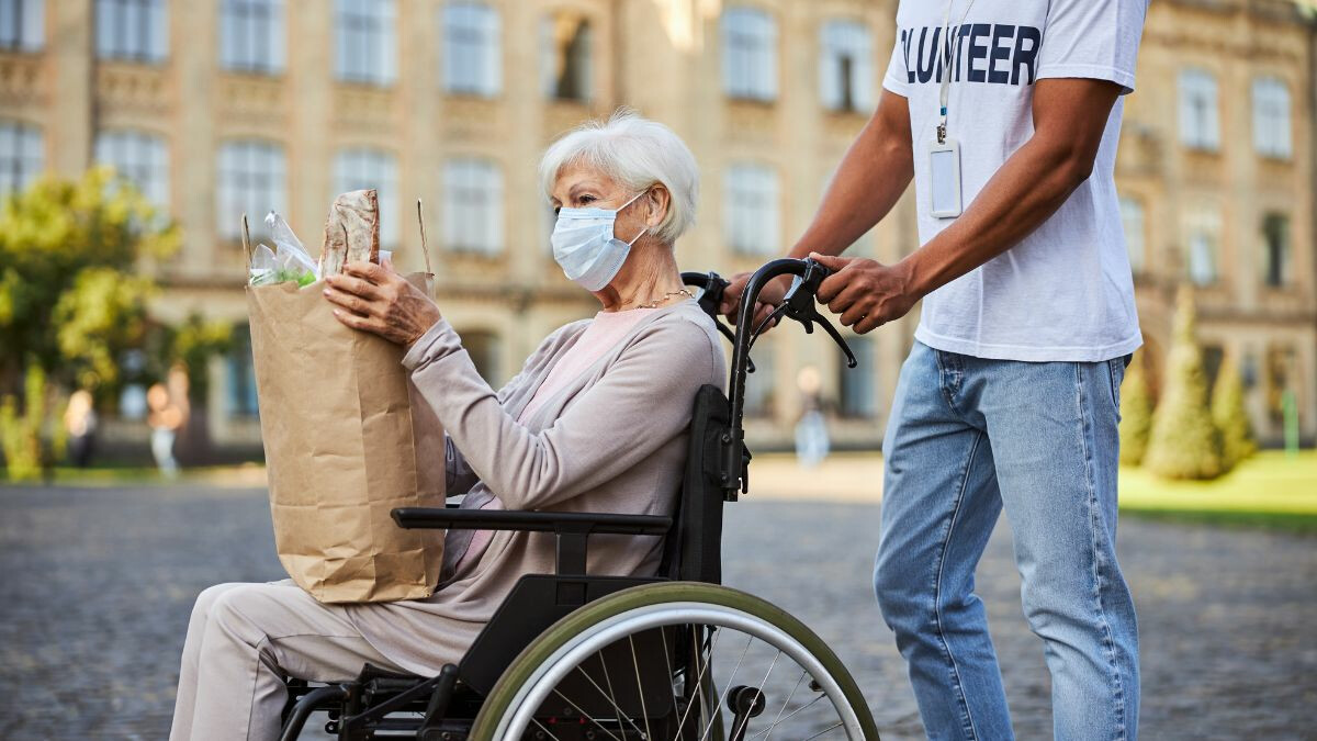 male-volunteer-pushing-elderly-woman-in-wheelchair