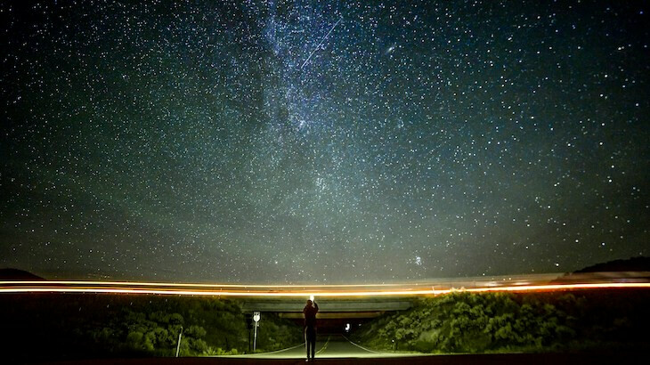 A woman captures a photo of the starry sky