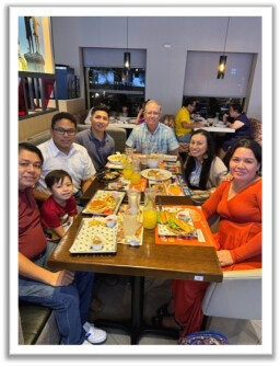 group of people sitting at a restaurant table and smiling at the camera
