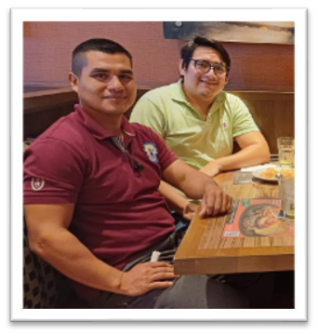 Two men sitting at a restaurant table in a booth looking an the camera