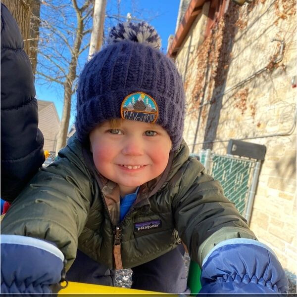 A boy with rosy cheeks in a stocking cap and down coat.