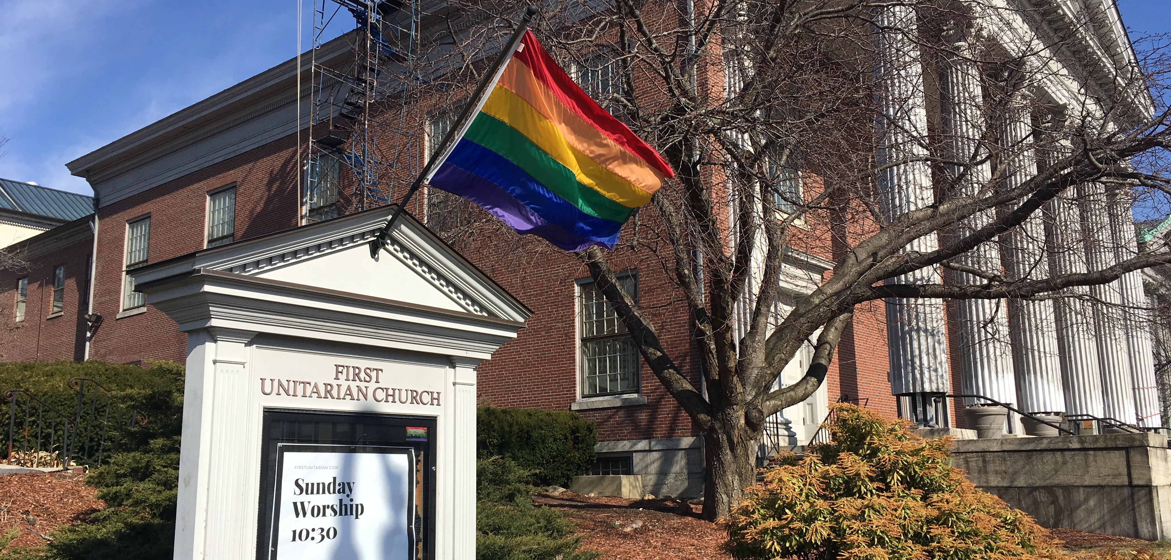 Wayside pulpit with rainbow flag in front of First Unitarian Church