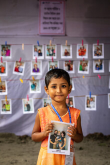 A little girl holding a picture of a family that she chose to be her sponsor.