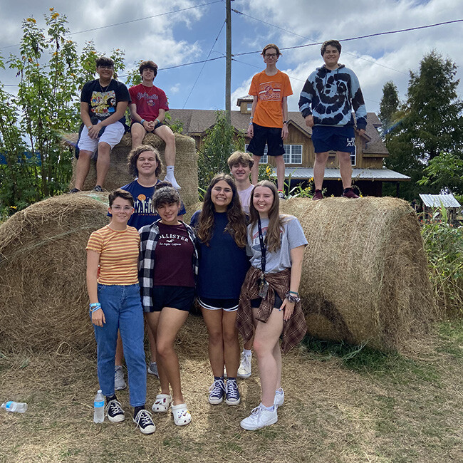 Students posing on haystacks