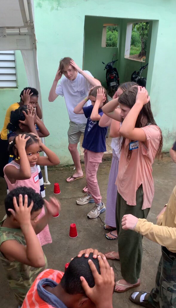 group of children with their hands on their heads as motions in a song