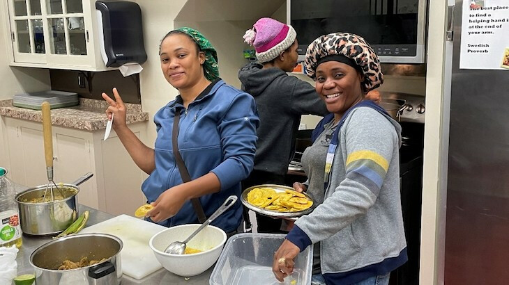 Three women smile while cooking in the church kitchen