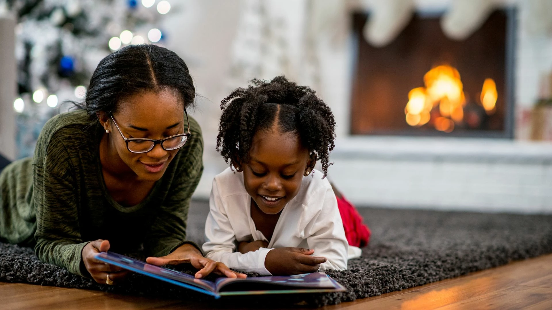 mom-and-young-daughter-reading-Christmas-books-by-the-tree