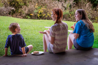 Youth volunteers picnic with a little boy during an Appalachia Service Project trip