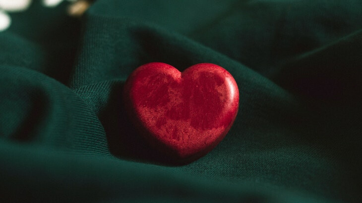 Red wooden heart on green cloth