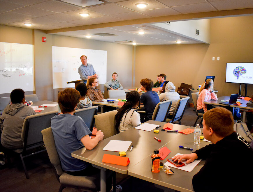Students gather in a classroom with professor teaching faith integrated curriculum