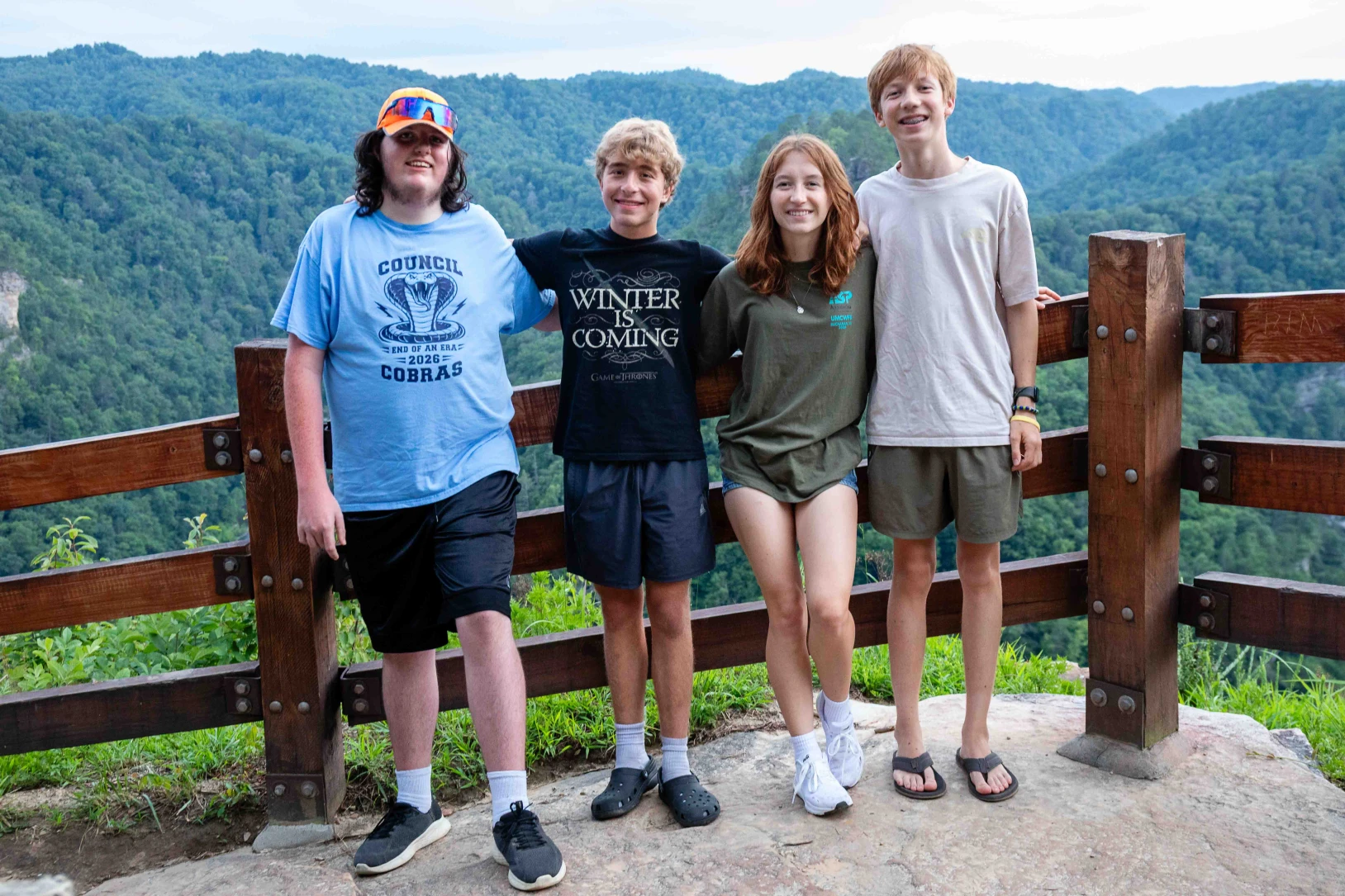 Youth on a mission trip pause for a picture above a forested river valley in Appalachia.