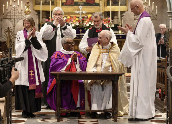 Presiding Bishop Michael Curry and Archbishop of Uppsala Martin Modéus sign a full communion agreement between The Episcopal Church and the Church of Sweden during a March 27 service held at the Cathedral Church of the Holy Trinity in Paris, France. They are surrounded by from left, the Rev. Margaret Rose, the Rt. Rev. Pierre W. Whalon, the Rt. Rev. Mark Edington and the Rev. Christopher Meakin. Photo: Jeremy Tackett