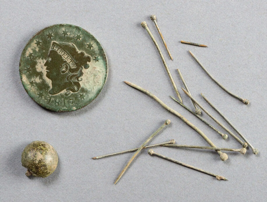 An old coin and a pile of pins