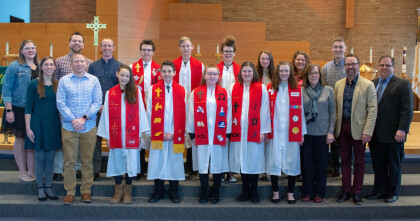 confirmation students in white robes with red stoles, along with pastors and youth leaders