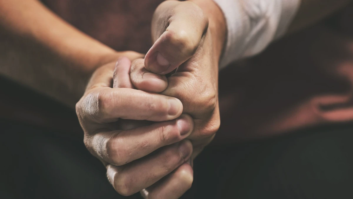 Two people holding hands in prayer