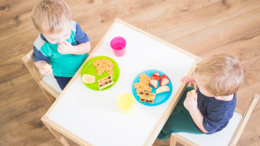 2 toddlers eating lunch at table