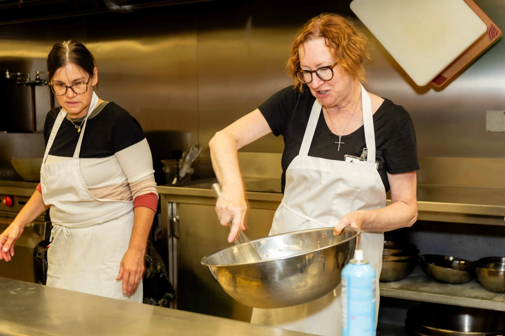 Women prepare meals to be served to a group.