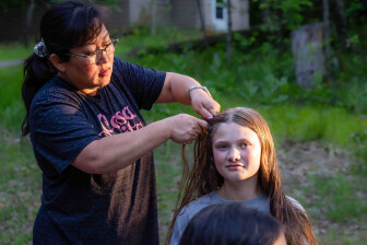 Adult volunteer braiding a child's hair during church camp