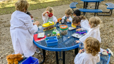 kids outdoors studying bugs with magnifying glasses