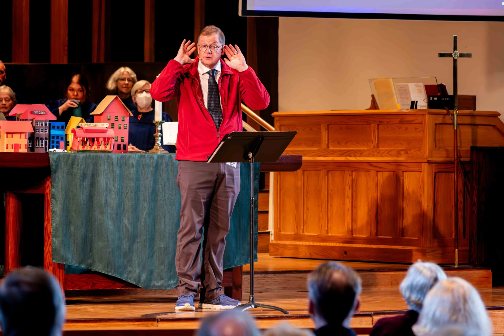 Pastor Gary Holmes holds his hands to his ears as he delivers a sermon.