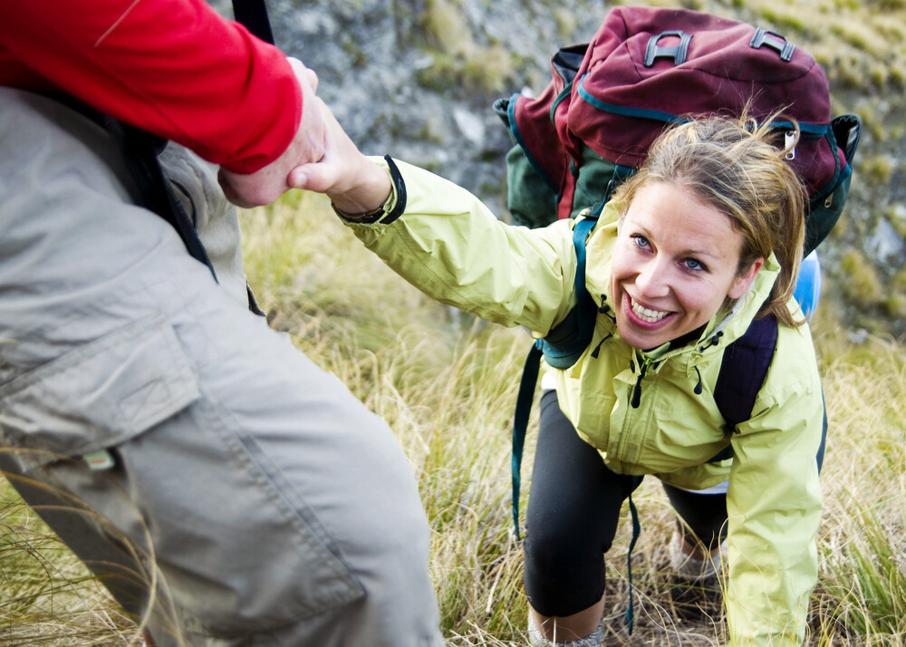 man-helping-female-hiker-up-a-steep-slope