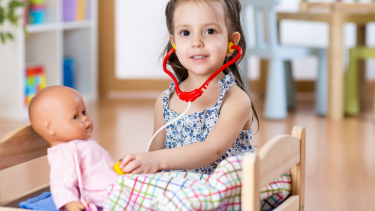 girl listening to doll's hearbeat with toy stethoscope