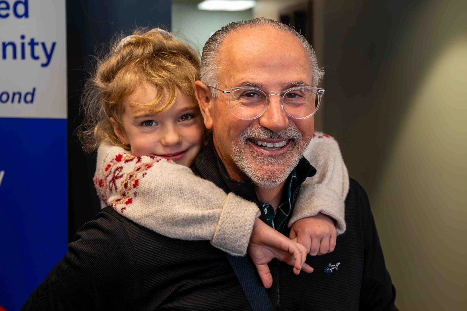 A young girl rides on the shoulders of her smiling grandfather.