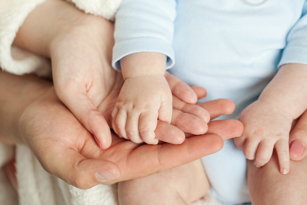 close-up-of-mom-and-dad-holding-babys-hands