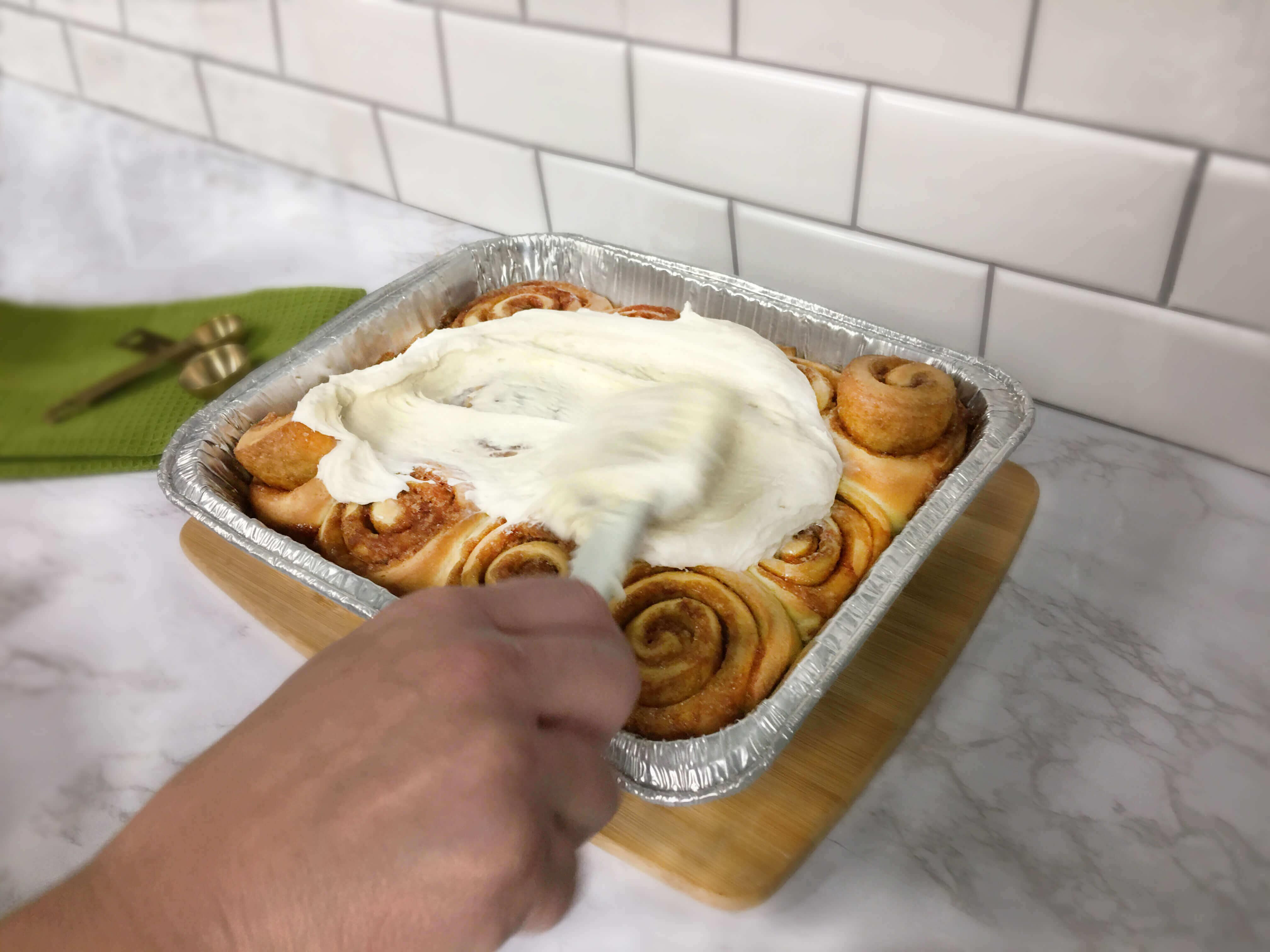 spreading-frosting-on-homemade-cinnamon-rolls