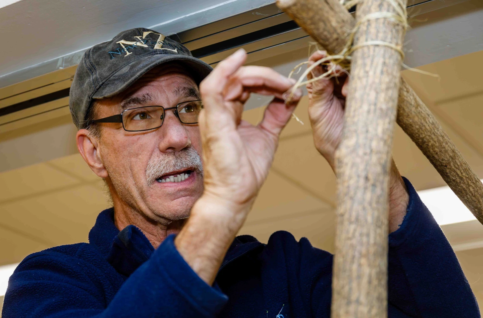 A man carefully ties poles together with twine for the Journey to Bethlehem experience.
