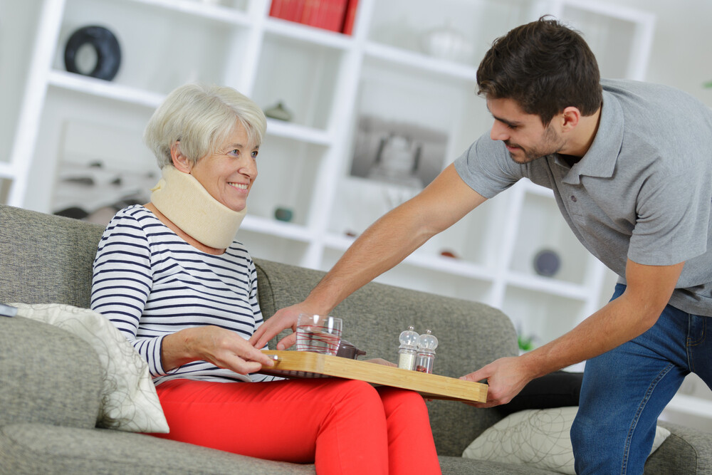 young-man-helping-elderly-woman-with-lunch-tray