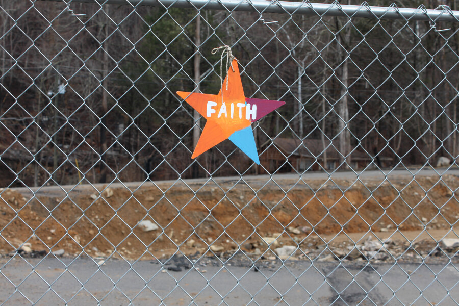 FAITH sign hanging on fence at building site