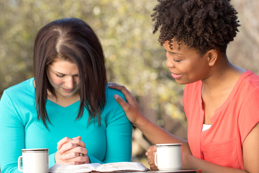 two-women-praying-together-with-Bible-and-coffee