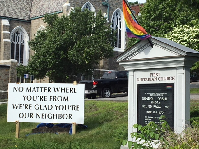 A sign in front of the church reads "No matter where you're from, we're glad you're our neighbor"