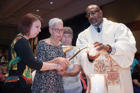 Rev. Joseph Daniels assists a family in lighting a candle in memory of a loved one during the Memorial Service.