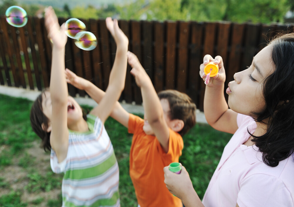 group-of-happy-kids-playing-with-bubbles-in-the-yard