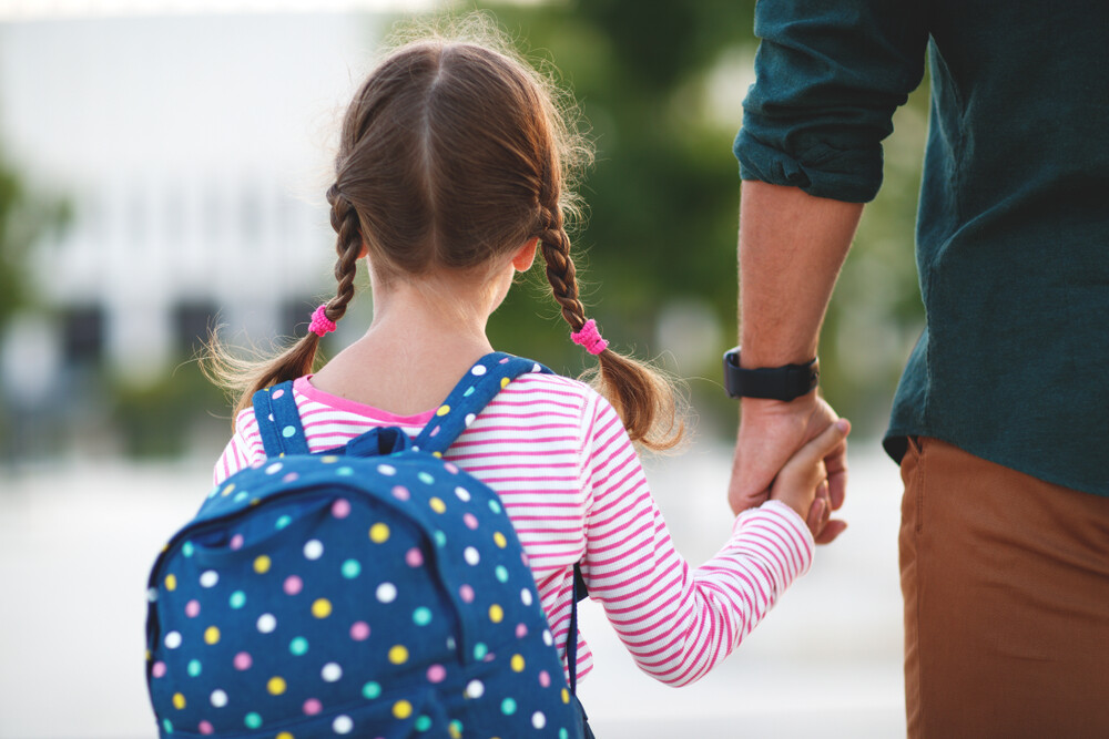 father-holding-his-young-daughter's-hand-with-backpack