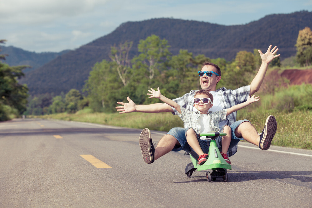 young-father-and-son-riding-a-small-scooter-being-silly