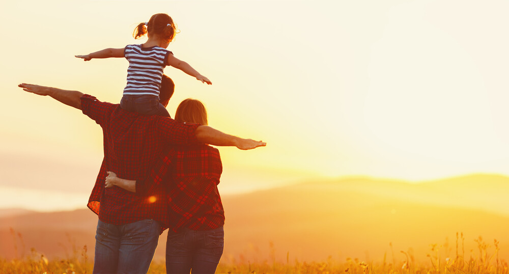 mother-father-and-daughter-in-nature-watching-a-sunset